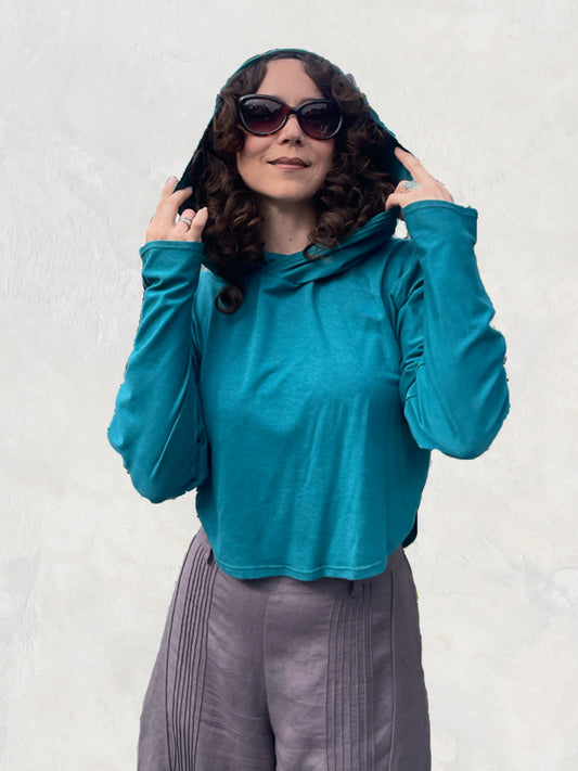 Woman in a super soft sunproof hoodie, teal color wearing big sunglasses looking happy