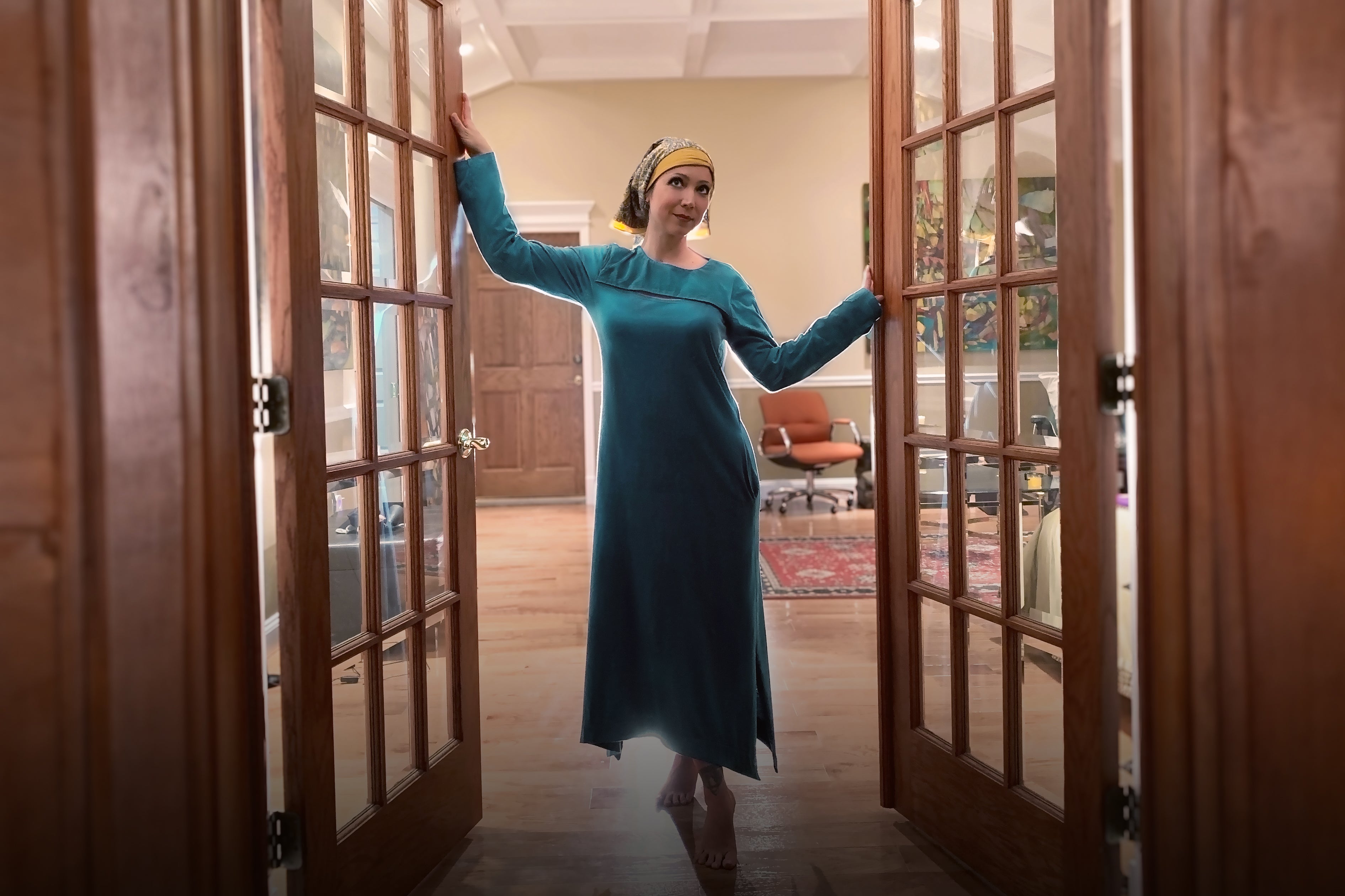 lady in doorway wearing a beautiful long teal dress that is medically accessible adaptive wear, that can be scanned and have a chest port infusion. 