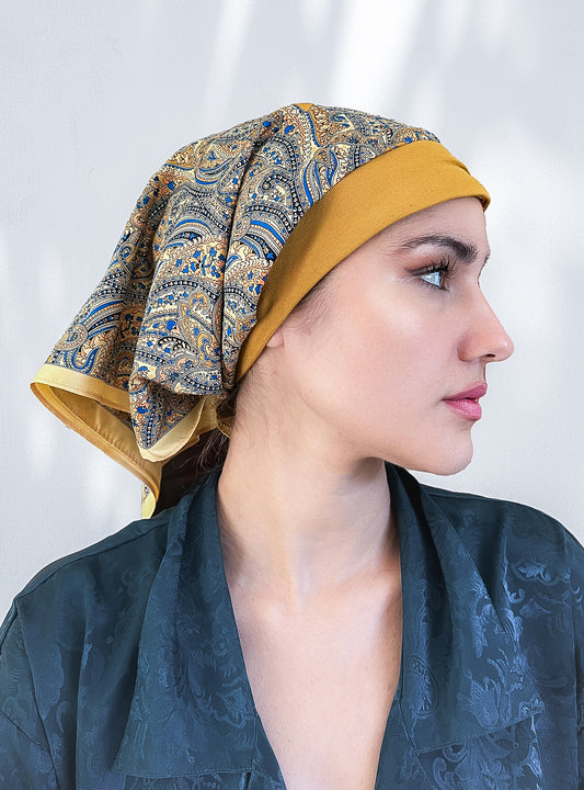 beautiful woman wearing a fashionable headscarf, of gold and paisley, in the retro kerchief style, designed specifically for those experiencing hair loss