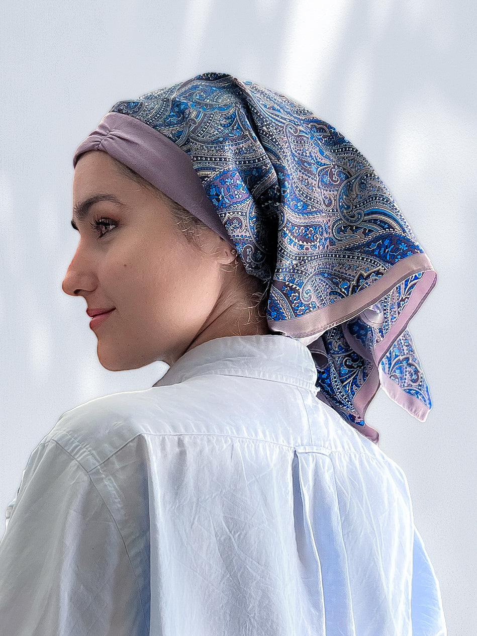 beautiful woman wearing a fashionable headscarf, of lavender and paisley, in the retro kerchief style, designed specifically for those experiencing hair loss