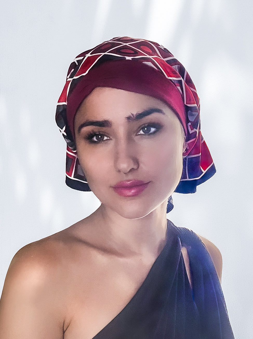 beautiful woman wearing a fashionable headscarf, of ruby red and black with geometric shapes , in the retro kerchief style, designed specifically for those experiencing hair loss