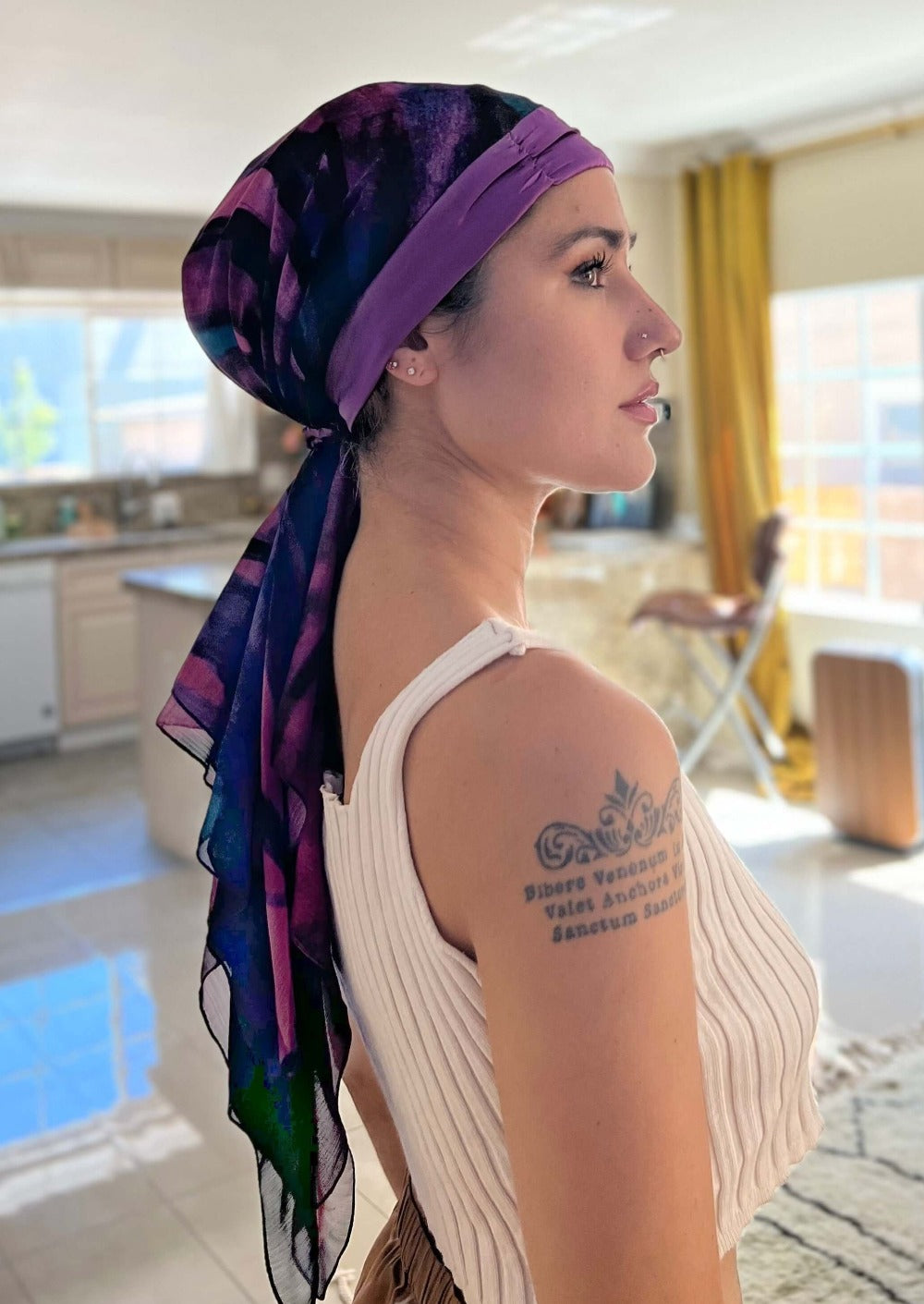 Woman wearing a headscarf , Boysenberry, purple and wine colored chiffon and silk. It hangs down long in the back and is very dreamy.
